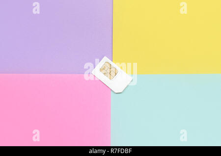 Subscriber identity module. New white SIM card on bright multicolor background. Minimal flat lay top view. Violet, pink, yellow and blue pastel colors Stock Photo