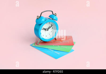 Small blue alarm clock lies on colored credit cards. The concept of modern fast online banking and funds transfer operations Stock Photo