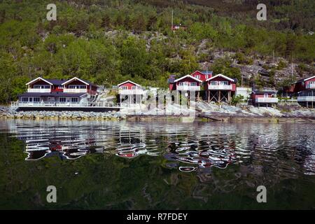 rorbuer - traditional norwegian red wooden house to stand at the lakeside and mountains in the distance, norway Stock Photo