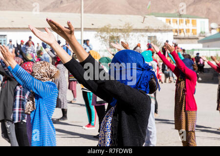 Murghab, Tajikistan, August 23 2018: Kyrgyz girls and young women are practicing a dance on the playground of a school in Murghab. Against the strong  Stock Photo