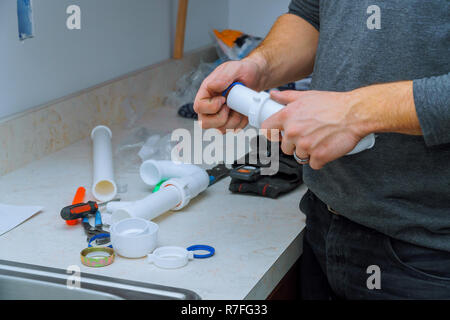 plumber fitting pipes of tools and equipment in a kitchen install a kitchen sink Stock Photo