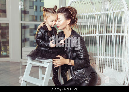 Portrait of a young mom and her daughter in black leather jackets. Stock Photo