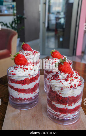 Strawberry trifle in jar with fresh strawberry on top on wood plate