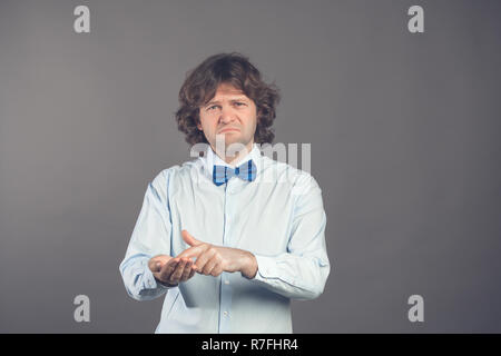 Man in shirt and tie shows outstretched hand with open palm, index finger pointing at palm. Upset man asks for money. Lack of money concept. Asking for help, financial assistance. Financial meltdown Stock Photo