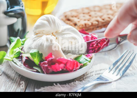 Burato cheese and lettuce for weight correction of Lollo Rosso lettuce leaves, watercress salad and other green herbs. The concept of healthy eating.  Stock Photo