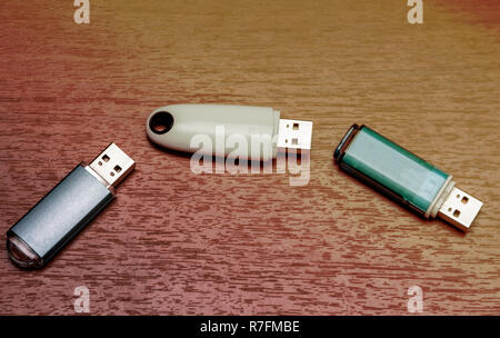 Three USB flash drives are located on a wooden surface. Stock Photo
