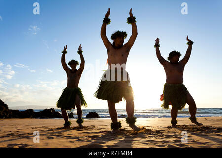 Three male hula dancers at sunset at Wailea, Maui, Hawaii Stock Photo