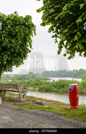 Belleville nuclear power plant, on the shores of the Loire in France on a foggy day, with a fire hydrant and a bench in the foreground. Stock Photo