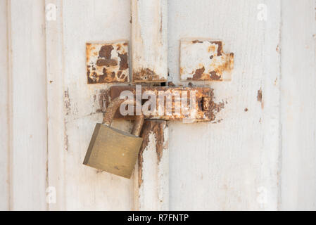 Old and rusty metal padlock on white doors. Closed door with lock Stock Photo