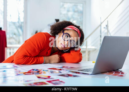 Upset young extravagant woman leaning on her desk Stock Photo