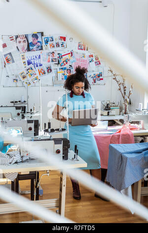 Short-haired concentrated female designer staying in sewing studio Stock Photo