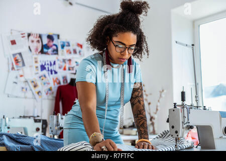 Curvy African American with short hair working with sewing machine Stock Photo