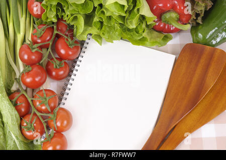 Selection of salad vegetables with blank recipe book or shopping list on a check tablecloth. Stock Photo