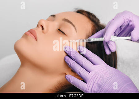 Woman receiving Botulinum Toxin Injection injection into eyes area . Stock Photo