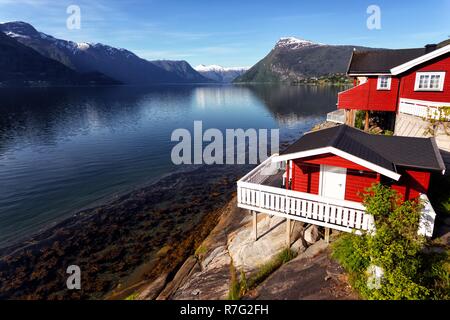 rorbuer - traditional norwegian red wooden house to stand at the lakeside and mountains in the distance, norway Stock Photo