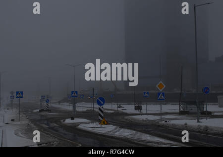 Heavy fog, road works in the city in cloudy snowy weather, repair of a pedestrian crossing, repair of asphalt, installation of road signs. Stock Photo