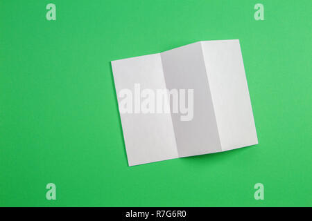 Mockup of blank white tri fold booklet brochure on green background. Stock Photo