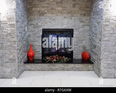 Gas fireplace in gray brick enclosure with red vase on the sides Stock Photo