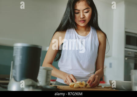 Woman preparing healthy juice from fruits in the kitchen. Female making a smoothie in the morning after workout. Stock Photo