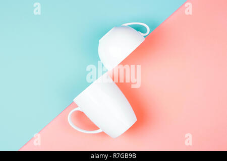 Two white cups on color background. Abstract, top view. Living coral and Limpet shell. Trendy colors of the 2019. Stock Photo