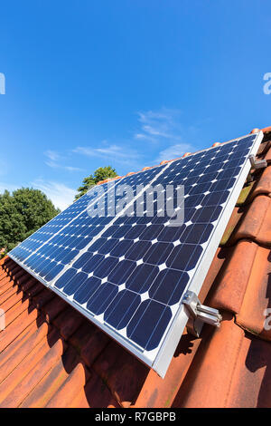 Blue solar panels  in a row on roof of house with sky Stock Photo