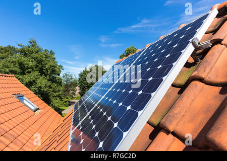 Row of blue solar collectors  on orange roof of house Stock Photo