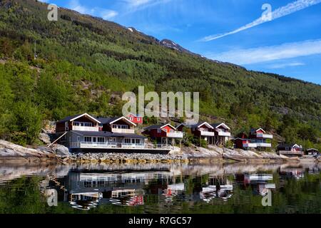 rorbuer - traditional norwegian red wooden house to stand at the lakeside and mountains in the distance, norway Stock Photo