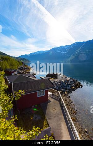 rorbuer - traditional norwegian red wooden house to stand at the lakeside and mountains in the distance, norway Stock Photo
