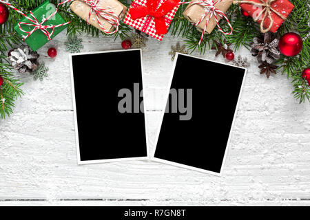 christmas blank photo frames with fir tree branches, decorations and gift boxes over white wooden background. mock up. flat lay. top view Stock Photo