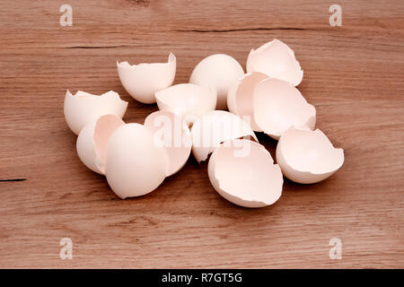 A pile of empty white egg shells lying on a wooden board surface Stock Photo