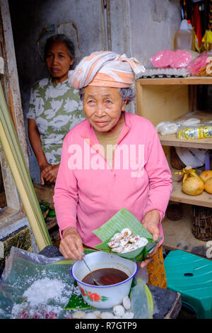 An elderly lady manning a market stall in Bali, Indonesia Stock Photo