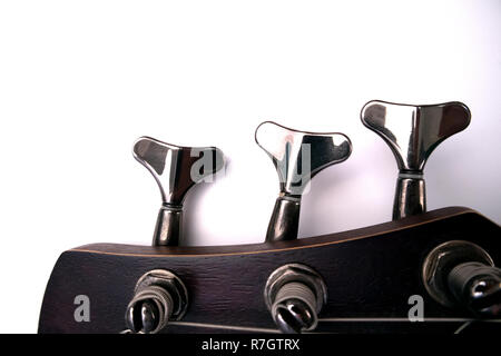 Bass guitar pegs on the head of the neck closeup isolated on white background Stock Photo