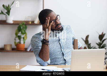 Serious thoughtful african businessman sitting at desk  Stock Photo
