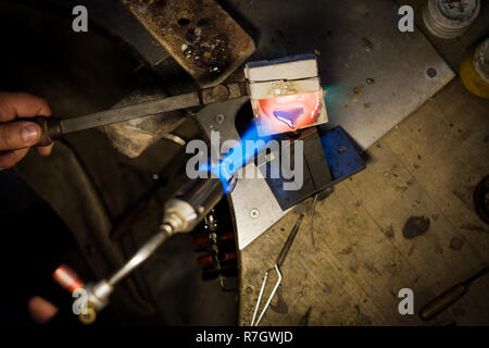 Jeweler pouring with flame melted silver or gold in metal form at jeweler's workshop Stock Photo