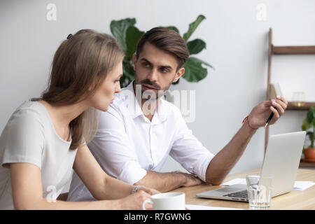 Serious workmates discussing arguing working using laptop Stock Photo