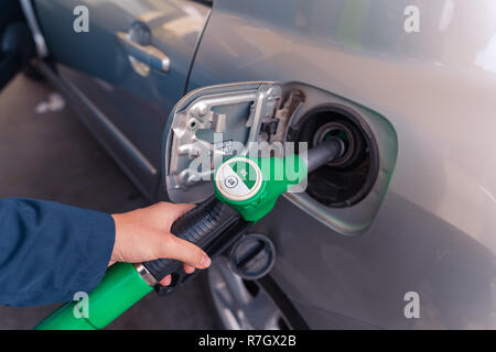 Fuel pistols at european Petrol station. Woman's hand  putting 95 E5 fuel  green pistol to the fuel tank. Focus on the pistol. Stock Photo