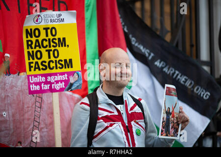 London, UK. 9th Dec, 2017. A representative of the organisation 'Football Against Apartheid' holds an Anti-Facism sign and poses next to the Palestinian flag.3,000 Pro-Brexit demonstrators and 15,000 Anti-Facist counter demonstrators took to the streets of London to voice their stance on the deal ahead of the key Brexit vote in parliament this Tuesday. Credit: Ryan Ashcroft/SOPA Images/ZUMA Wire/Alamy Live News Stock Photo