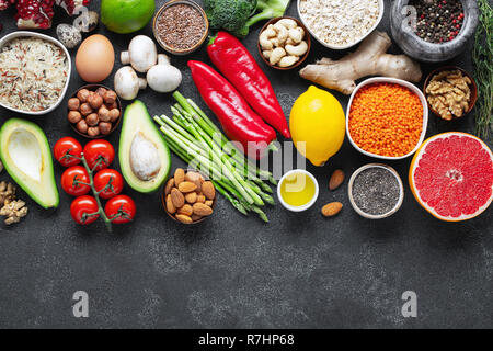 Healthy food clean eating selection: fruit, vegetable, seeds, superfood, cereal, leaf vegetable on black concrete background. Flat lay. Stock Photo