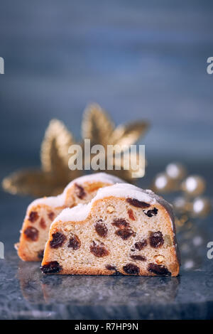 Christmas stollen on dark blue festive background with golden decorations and copy-space. Traditional German dessert for Christmas celebration. Stock Photo