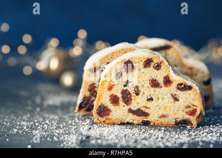 Christmas stollen on dark blue festive background with Xmas lights. Traditional German dessert for Christmas celebration. Stock Photo