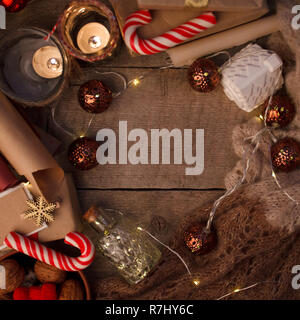 cozy winter composition with candles, traditional christmas sweetness, garland and sweater on a vintage wooden festive background, kinfolk style, flat Stock Photo