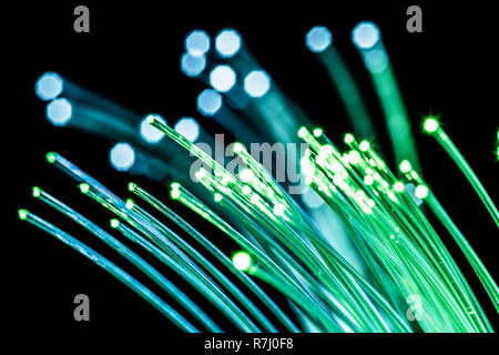 Bundle of optical fibers with green light. Black background. Stock Photo