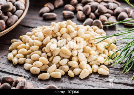 Pine nuts in the spoon and pine nut cone on the wooden table. Organic food. Stock Photo
