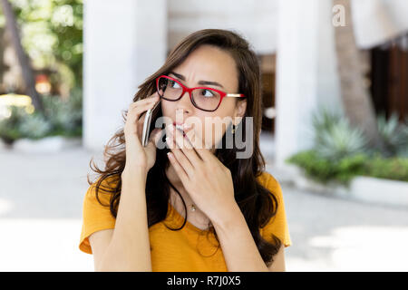 Woman with glasses receiving bad news on phone outdoor in the summer in the city Stock Photo