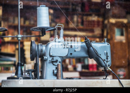 Old-fashined sewing machine in the sewing room. Working place of tailor. Stock Photo