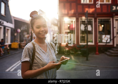 Smiling young Asian woman using her cellphone in the city Stock Photo