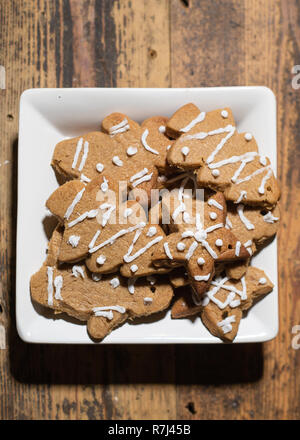 white square plate with various gingerbread biscuit shapes on wooden background, portrait composition Stock Photo