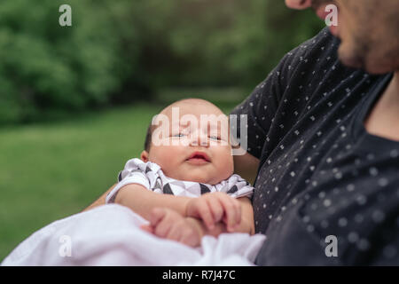 Cute baby boy being held by his father outside Stock Photo