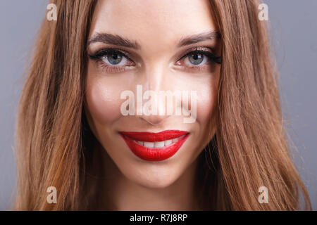 https://l450v.alamy.com/450v/r7j8rp/portrait-of-attractive-romantic-long-haired-woman-with-red-lips-wearing-black-dress-standing-and-smiling-on-the-gray-background-r7j8rp.jpg