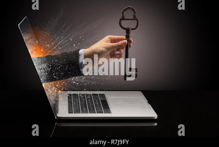 Hand with vintage huge key coming out of a laptop with sparkling effects Stock Photo